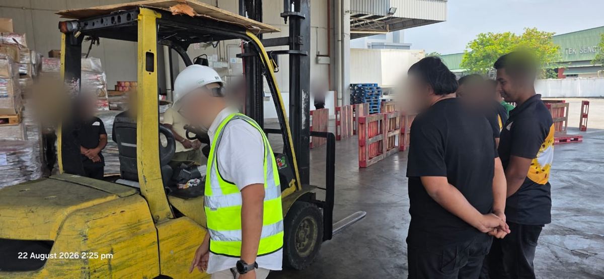 Trainer demonstrating a forklift inspection to warehouse workers